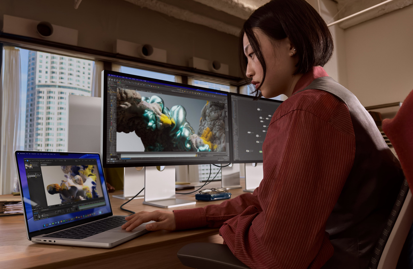 En person sidder ved en kontorplads og arbejder på en bærbar MacBook, der er forbundet til Studio Display XDR via en Thunderbolt 5-port