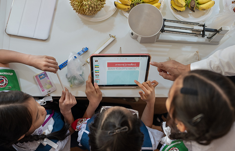 Tres alumnas de primaria colaboran en la presentación de un proyecto de ciencias alrededor de un iPad.